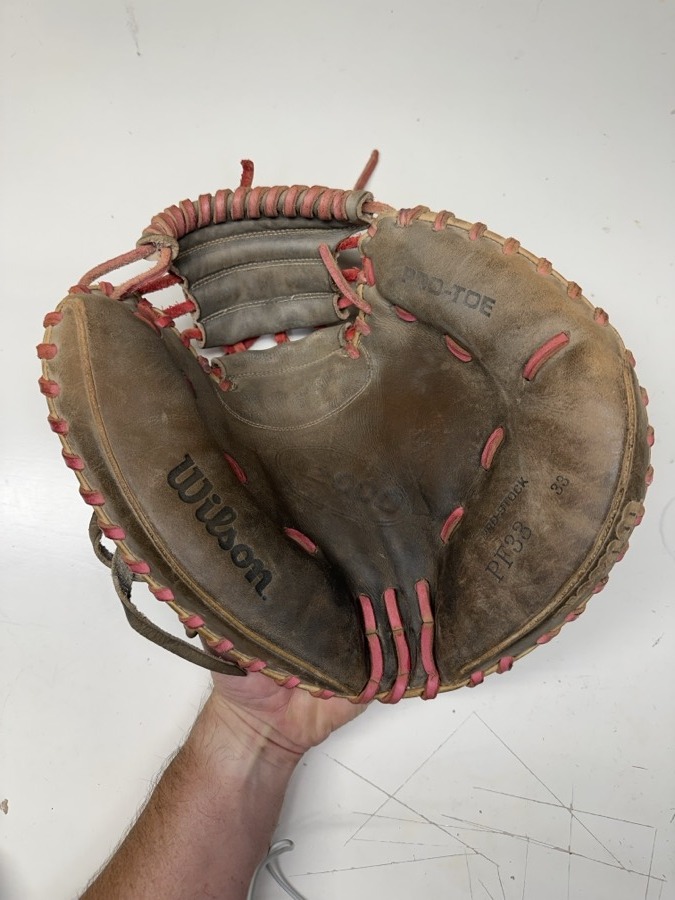 Wilson baseball glove before restoration — worn leather and frayed laces