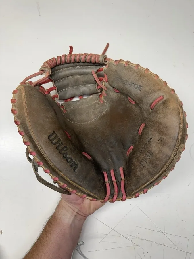 Wilson baseball glove before restoration — worn leather and frayed laces