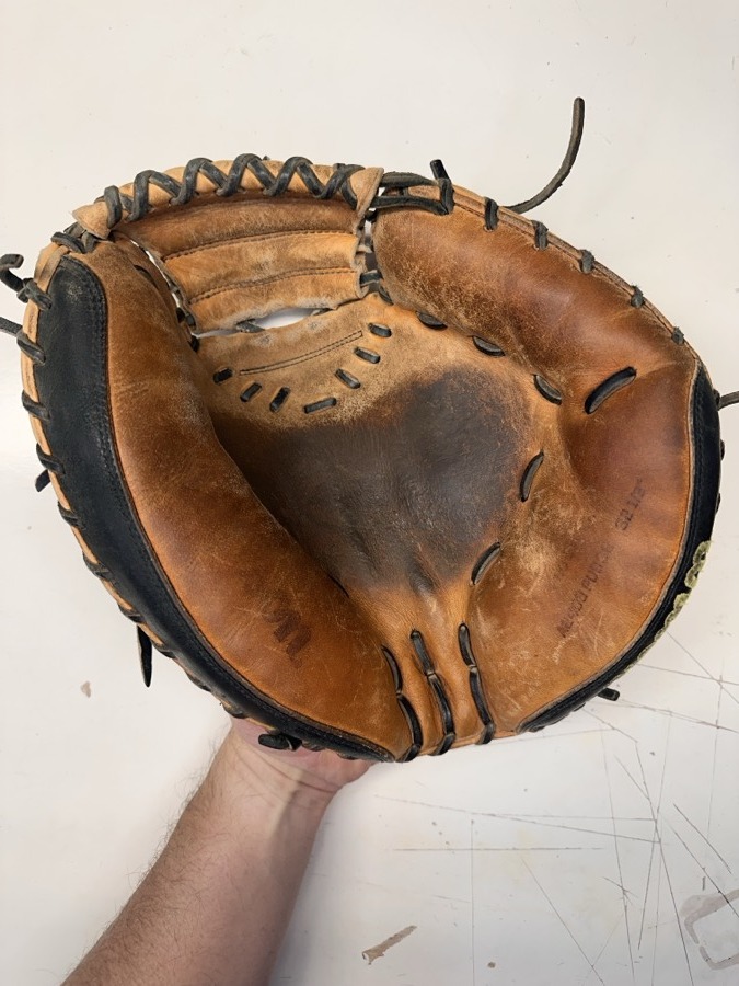 Wilson baseball glove before restoration — worn leather and frayed laces