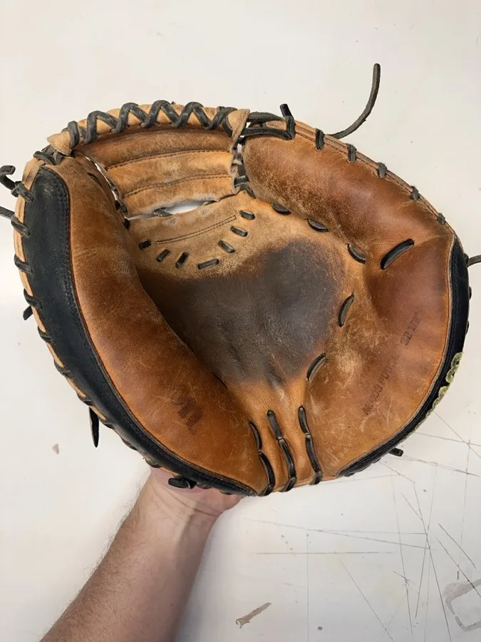 Wilson baseball glove before restoration — worn leather and frayed laces