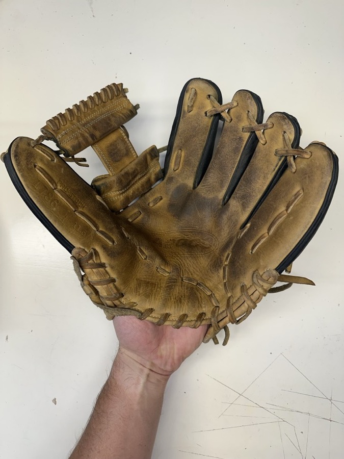 Wilson baseball glove before restoration — worn leather and frayed laces