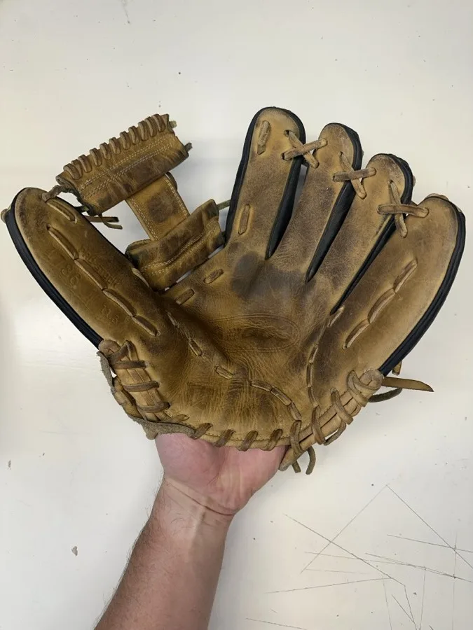 Wilson baseball glove before restoration — worn leather and frayed laces