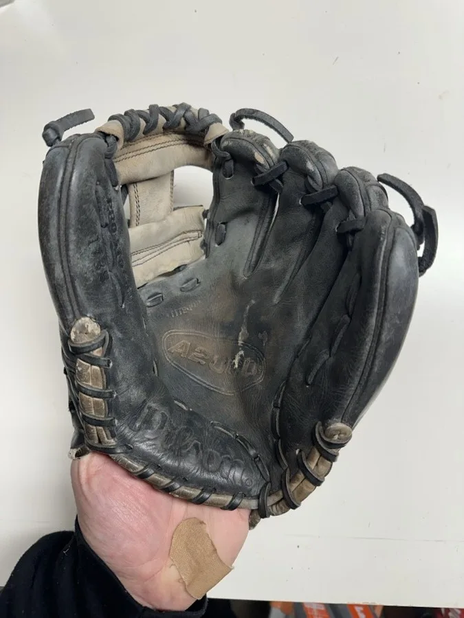 Wilson baseball glove before restoration — worn leather and frayed laces
