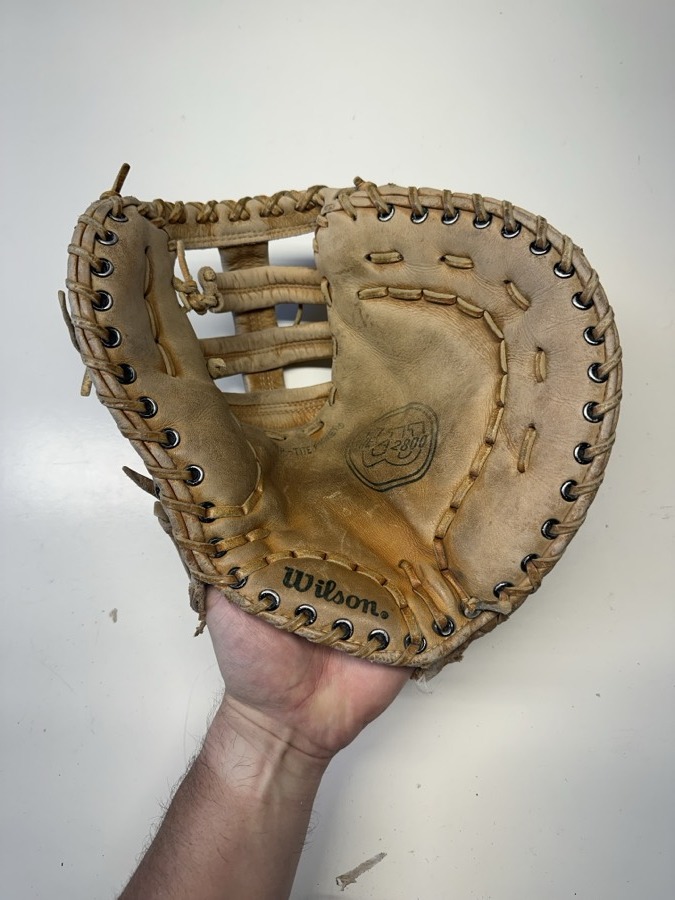 Wilson baseball glove before restoration — worn leather and frayed laces