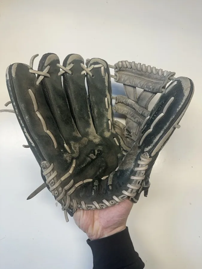 Wilson baseball glove before restoration — worn leather and frayed laces