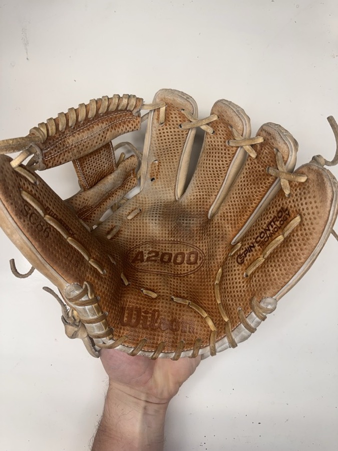 Wilson baseball glove before restoration — worn leather and frayed laces