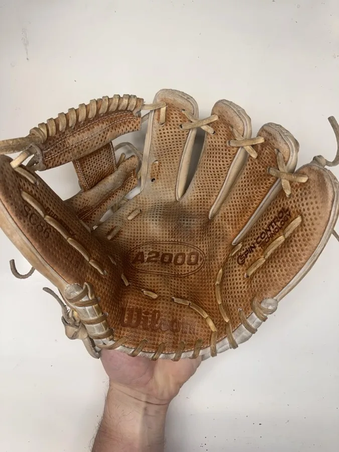 Wilson baseball glove before restoration — worn leather and frayed laces